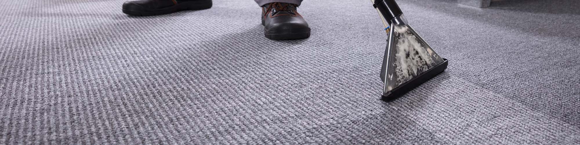 Technician running a hot-water extraction wand across commercial carpet